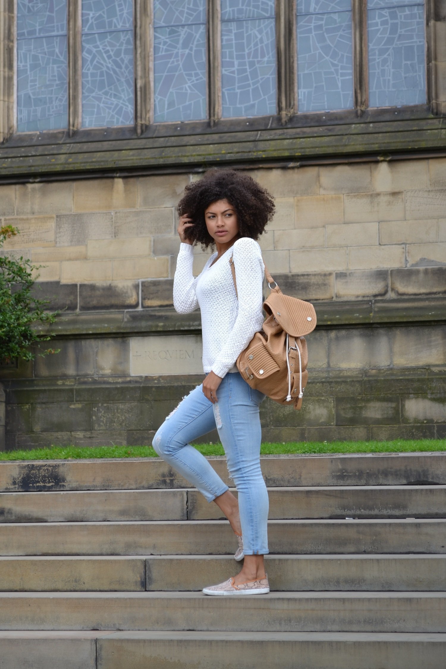 Samio wearing white Gap jumper and denim jeans with brown faux leather River Island backpack